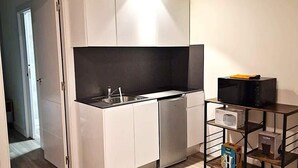 A compact kitchen with white cabinets, a black countertop, and a built-in oven. - Madrid Suites Brand new apartment - 4 (Madrid)