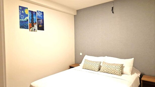 A bedroom with a bed, two pillows, a nightstand, and three paintings on the wall. - Madrid Suites Brand new apartment - 4 (Madrid)
