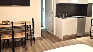 A compact hotel room with a dining table, chairs, a bed, a TV, and a kitchenette. - Madrid Suites Brand new apartment - 4 (Madrid)