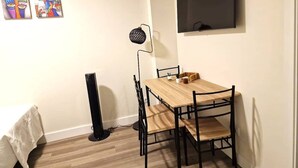 A small dining area with a wooden table and black chairs, a black floor lamp, and a TV mounted on the wall. - Madrid Suites Brand new apartment - 4 (Madrid)
