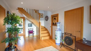 A spacious living room with a wooden staircase, a large vase, and a potted plant.