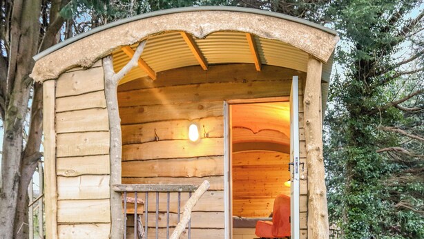 Eine Holzhütte mit einem Zimmer, einer kleinen Veranda und einem Stuhl im Inneren.