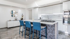 A modern kitchen with a central island, bar stools, a built-in oven, and a marble backsplash. - Luxury Penthouse Seaview Whit Terrace
 Giardini Naxos/Taormina (Giardini Naxos)