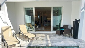 Un espace piscine avec des chaises longues et un ensemble de mobilier de jardin pour prendre les repas.