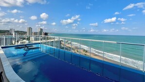 A rooftop pool with a view of the ocean and city skyline. - Edifício New Time - Apto1406 (Maceió)