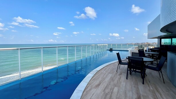 A rooftop pool with a view of the ocean and a cityscape. - Edifício New Time - Apto1406 (Maceió)