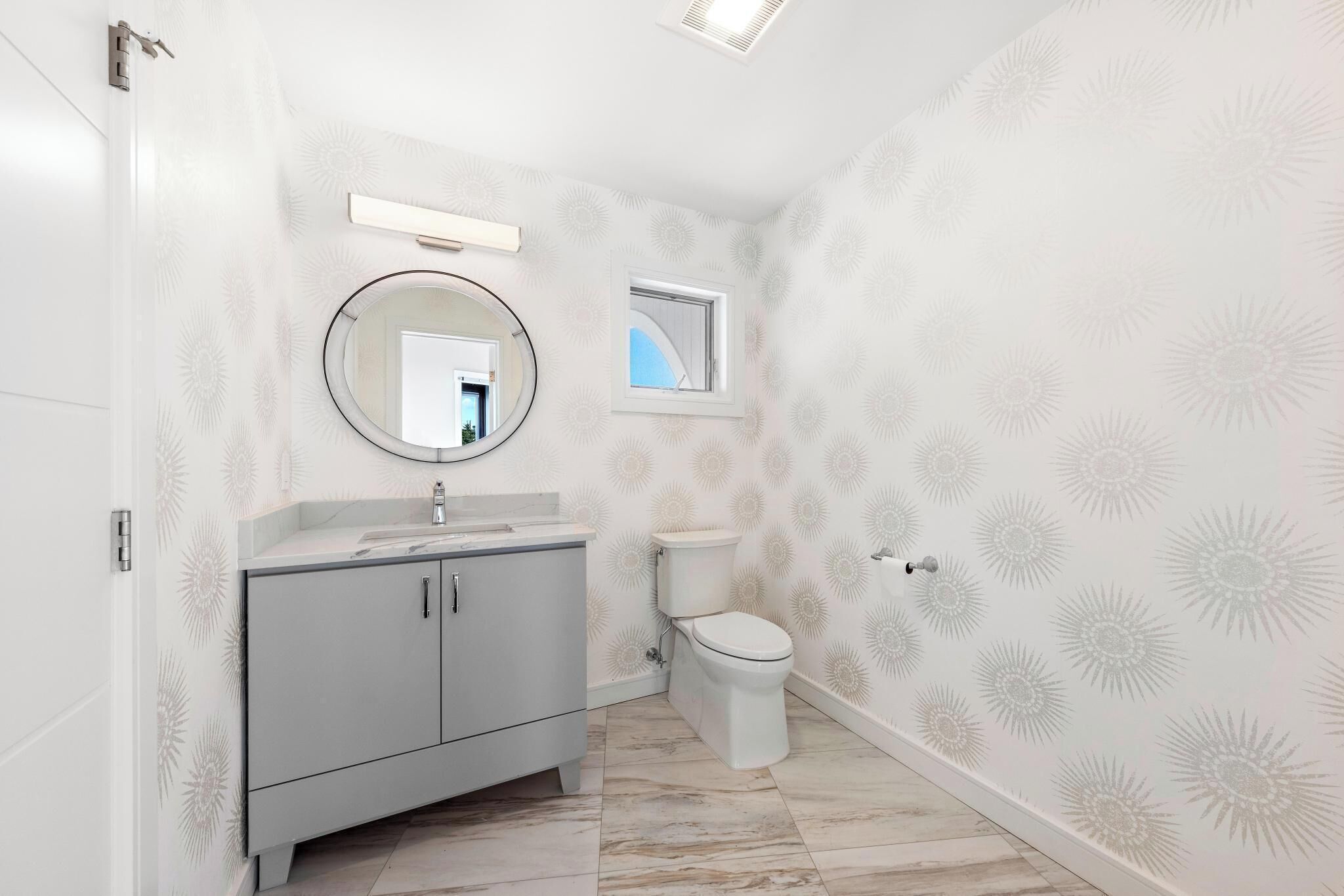 Une salle de bain avec des toilettes, un lavabo avec un miroir et une fenêtre.