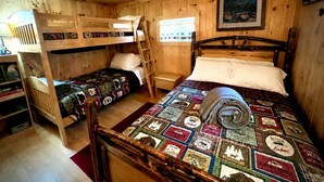 A cabin with two bunk beds, a wooden ladder, a quilted bedspread, and a framed picture on the wall. - Dog Friendly 🐾 Sleeps 8 • Near North Conway & Kancamangus Hwy. • Lake Access (Madison)
