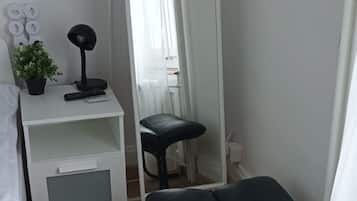 A bedroom with a bed, a bedside table with a lamp, a mirror, and a bench.