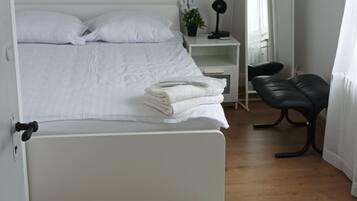 A bedroom with a bed, bedside table, lamp, and a painting on the wall.