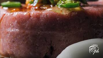 A close-up of a dish with a glossy sauce, garnished with green leaves and herbs.