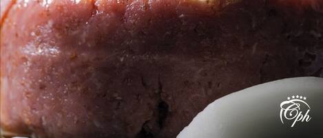 Primer plano de un plato con salsa brillante, adornado con hojas y hierbas verdes.