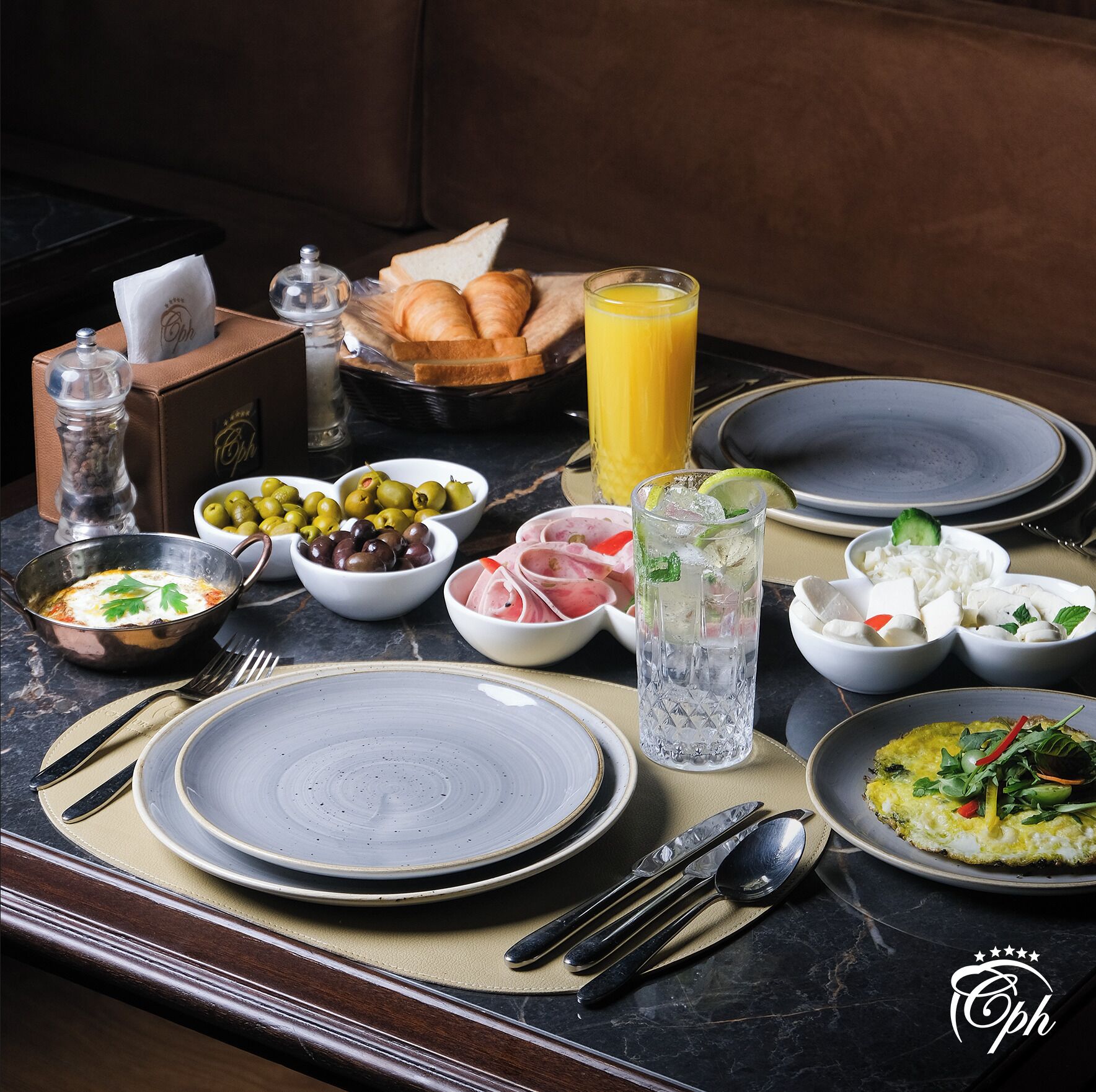 A breakfast setting with plates, bowls, and a glass of orange juice.