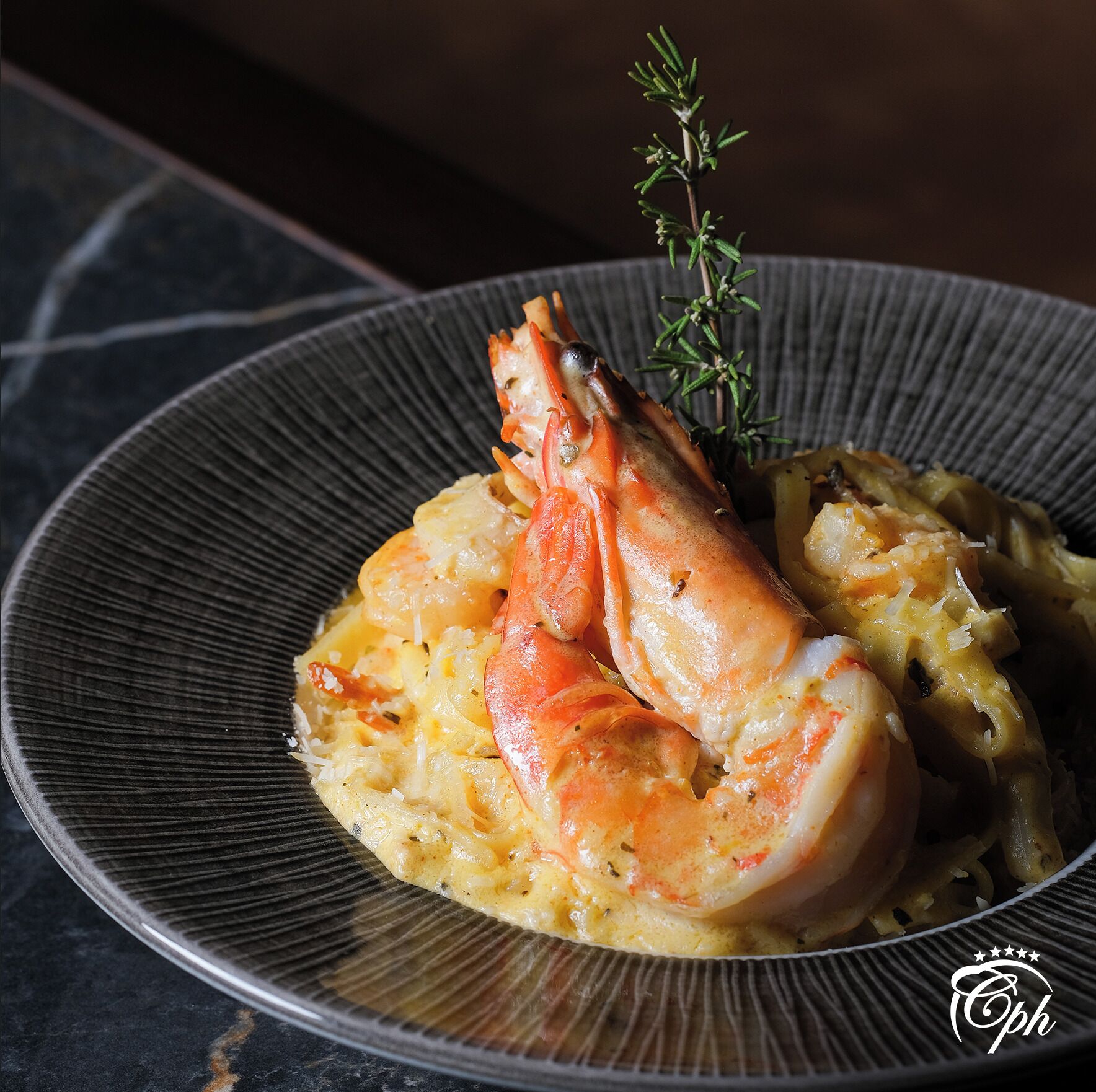 A plate with a lobster tail and a garnish of rosemary on a textured plate.