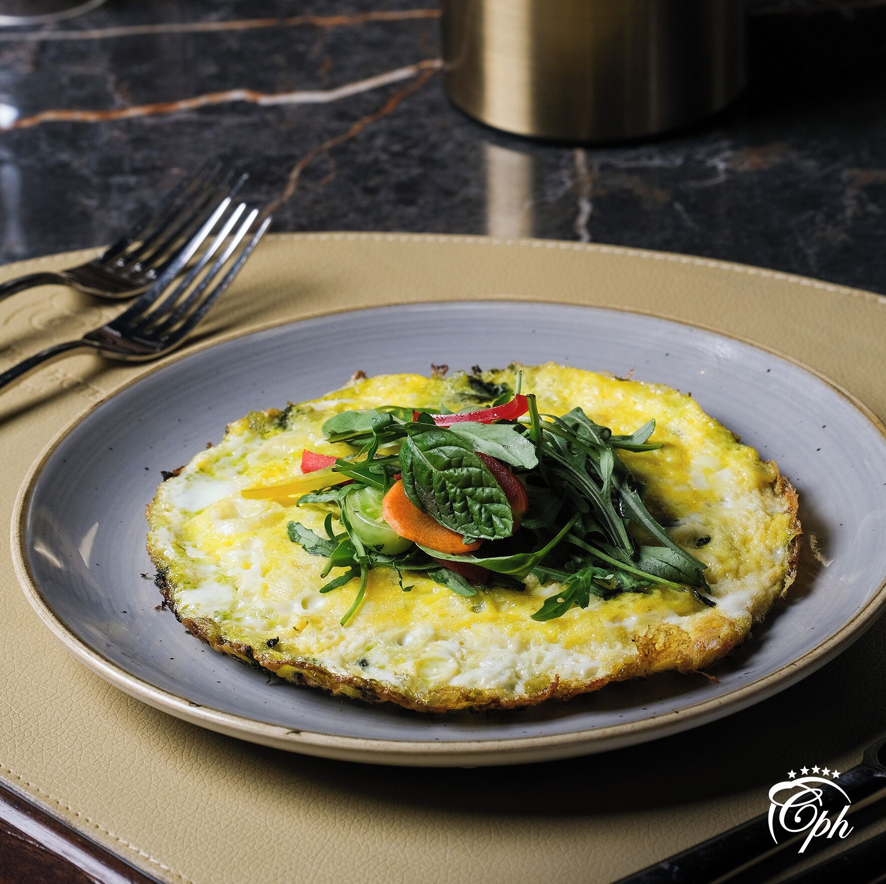 Un plat d'aliments amb diverses verdures i fulles verds sobre una base de tela beix.
