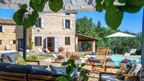 Eine Villa mit Swimmingpool, Sitzgelegenheiten im Freien und einem Garten.