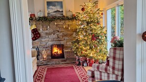 A cozy living room with a fireplace, a Christmas tree, and a 'MERRY' banner.