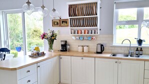A modern kitchen with white cabinetry, a wooden countertop, and a built-in shelf for dishes.