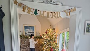A festive dining area with a Christmas tree, decorated table settings, and a 'Merry' banner.