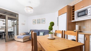 A modern kitchen with wooden cabinets, a microwave, and a dining area with a wooden table and chairs.