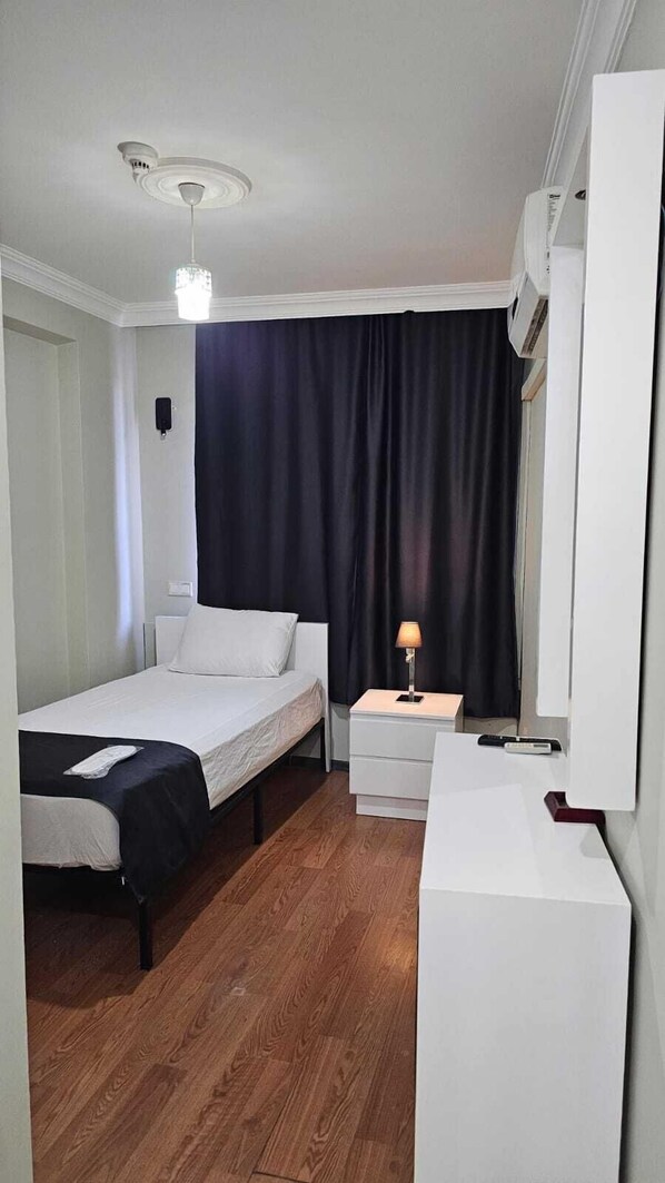 A small, neatly arranged bedroom with a bed, bedside table, lamp, and a mirror. - Sever Hotel (Antalya)