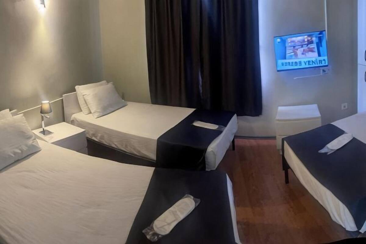 Una habitación de hotel con dos camas, un televisor en la pared y una mesita pequeña.