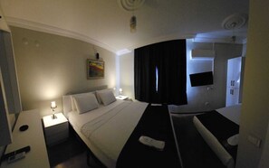 Een hotelkamer met een bed, nachtkastjes, een televisie en een schilderij aan de muur.