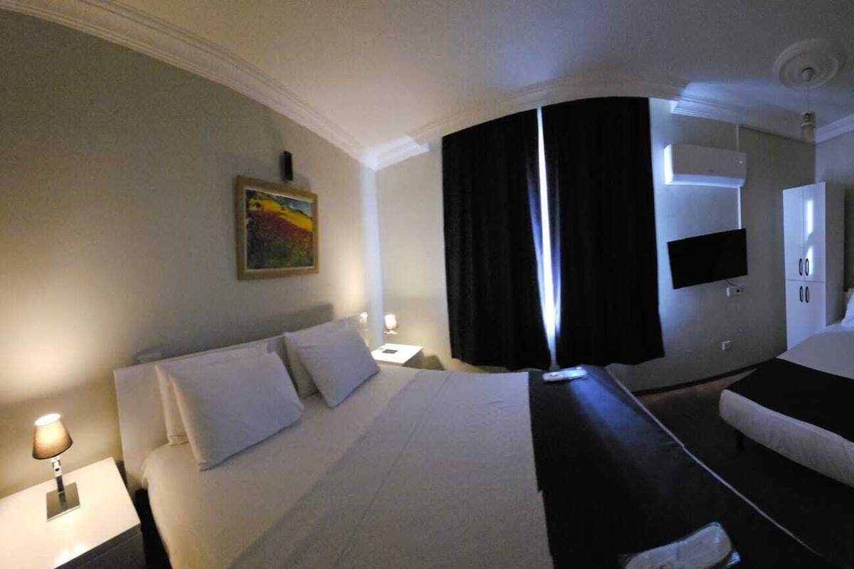Habitación de hotel con cama, escritorio, silla, televisor y un cuadro en la pared.