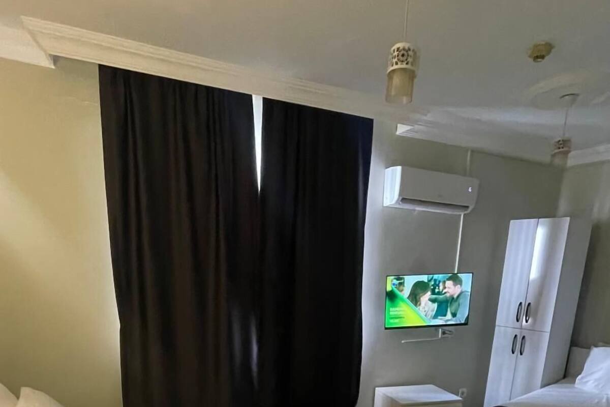 Una habitación de hotel con dos camas, televisión, aire acondicionado y ventilador de techo.