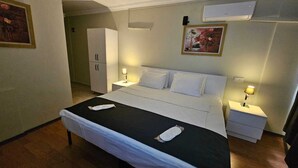 Una camera d'albergo con un letto, comodini, un armadio e un quadro appeso al muro.