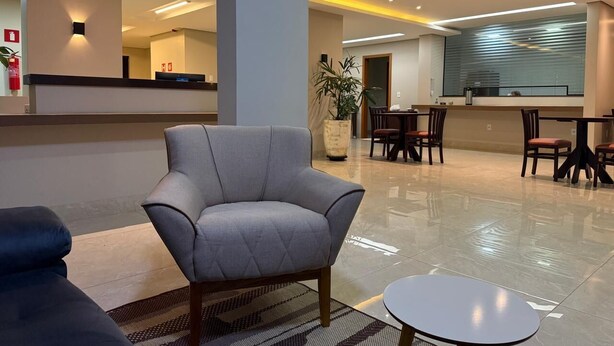 Een moderne lobby met een grijze fauteuil, een klein rond tafeltje en een receptiebalie.