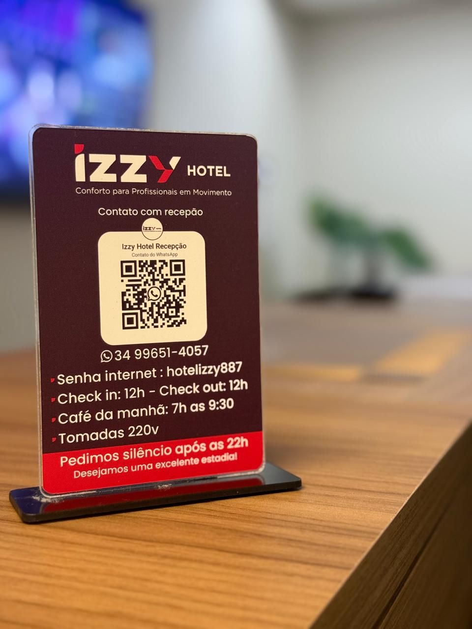 A hotel reception sign with a QR code, contact number, and amenities information.
