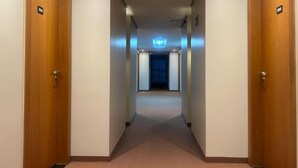Een hotelgang met houten deuren, genummerd 204 en 205, die leidt naar een kamer met een blauw gordijn.