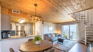 A spacious living area with a wooden dining table, a sofa, and a staircase leading to an upper level. - Mountain Views Indoor Pool Access Full Kitchen (Gatlinburg)