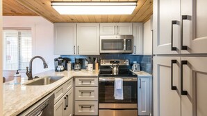A modern kitchen with stainless steel appliances, white cabinets, and a wooden ceiling. - Mountain Views Indoor Pool Access Full Kitchen (Gatlinburg)