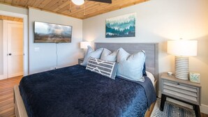 A bedroom with a bed, two bedside lamps, a ceiling fan, and a painting on the wall. - Mountain Views Indoor Pool Access Full Kitchen (Gatlinburg)