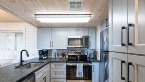 A modern kitchen with stainless steel appliances, a black countertop, and light grey cabinets.