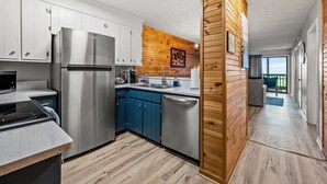 A modern kitchen with stainless steel appliances, blue cabinets, and a wooden accent wall. - Two Bed Room Condo Mountain Views Indoor Pool (Gatlinburg)