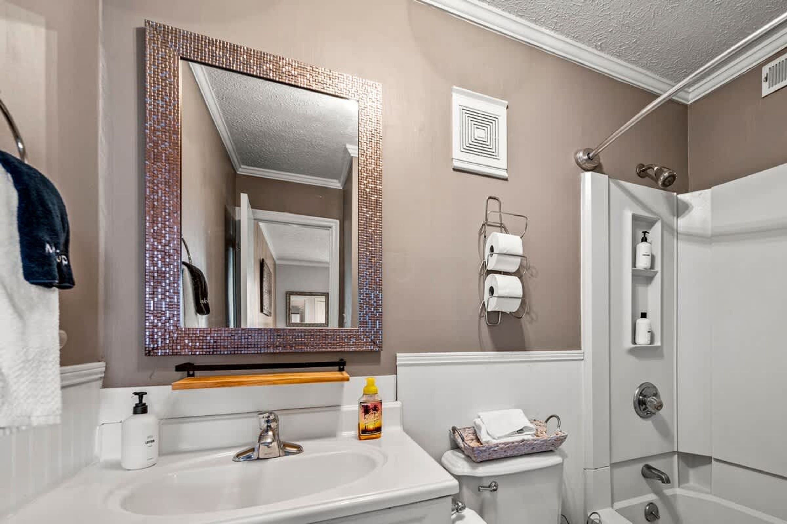 A bathroom with a large mirror, a sink, a toilet, and a shower.
