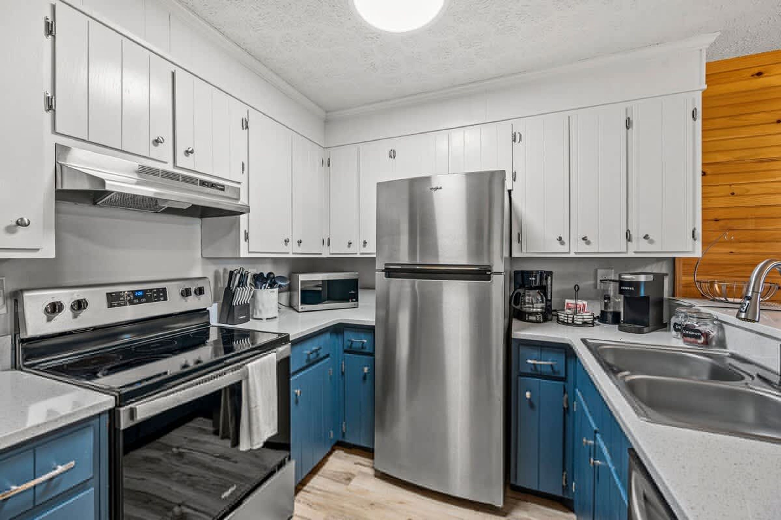 A modern kitchen with white cabinets, a stainless steel refrigerator, a microwave, and a stove.