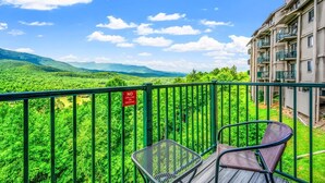 A balcony with a view of a lush green landscape and a building with balconies. - Sleeps 6 Full Kitchen Indoor Pool Mountains Views (Gatlinburg)