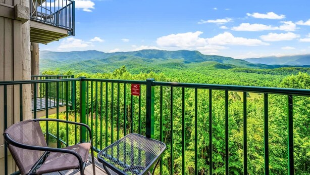 Un balcone con vista su dolci colline verdi e un cartello con la scritta 'NO GRILLING'.