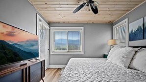 A bedroom with a bed, a TV, a ceiling fan, and a window with blinds. - Loft Sleeps 8 Views Indoor Pool Access (Gatlinburg)
