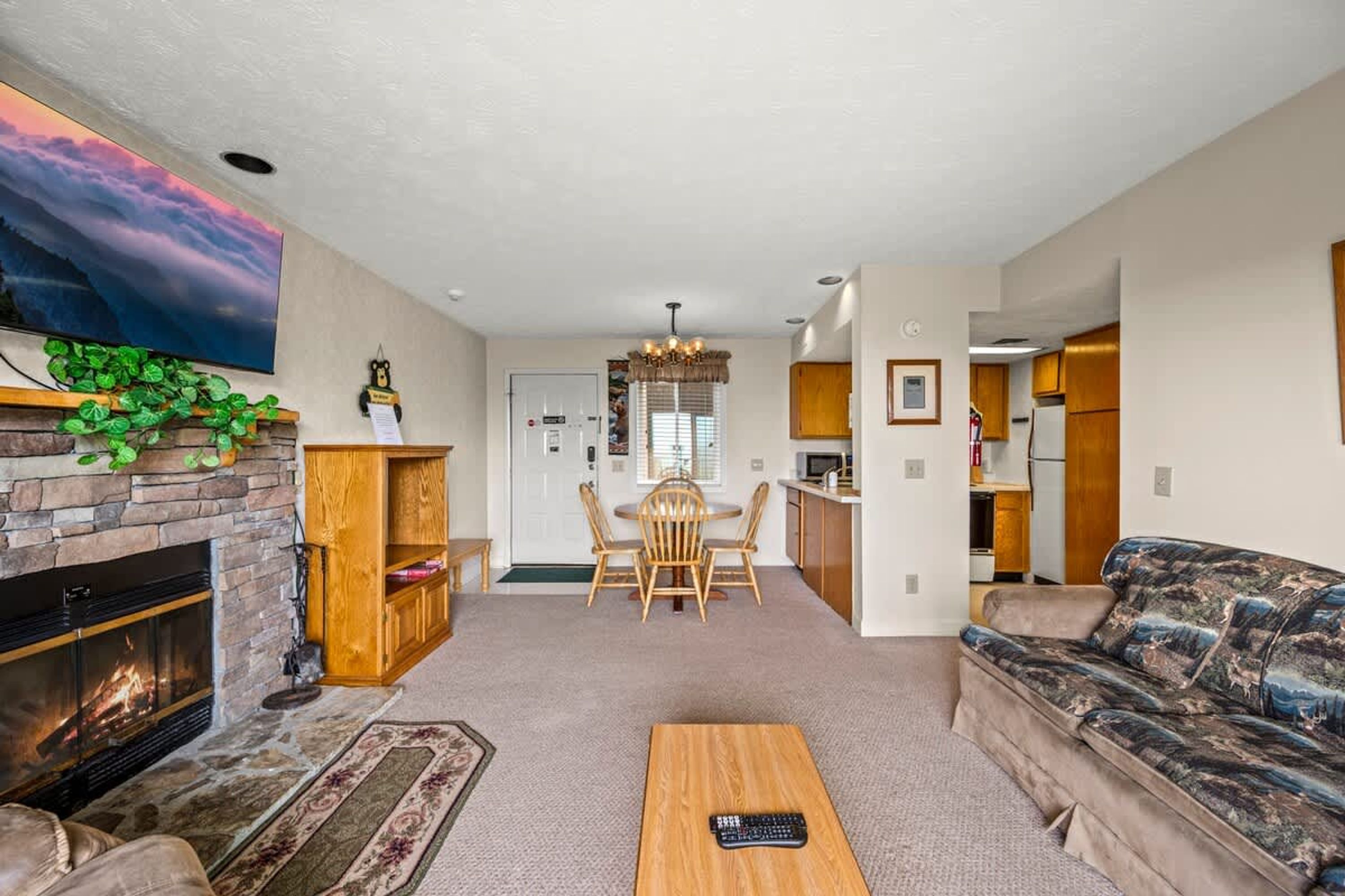 A living room with a fireplace, a sofa, a coffee table, and a dining area with a chandelier.