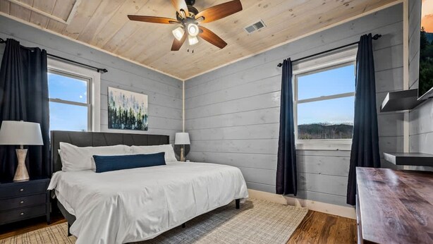 Una camera da letto con un letto, due comodini, una ventola a soffitto e una finestra con tende.