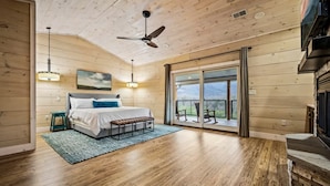 Una camera da letto con un letto, una panca, una ventola a soffitto, un'ampia finestra e vista sull'esterno.