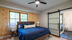 A bedroom with a bed, a ceiling fan, a window, and a sliding door.