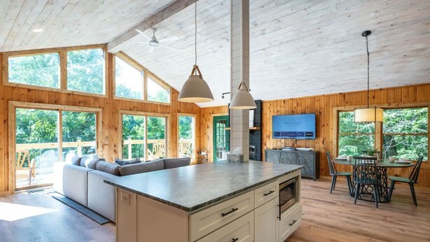 A spacious kitchen with a large island, wooden walls, and large windows.