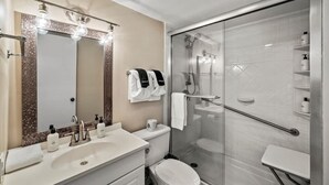 A modern bathroom with a large mirror, a sink with toiletries, a toilet, and a glass-enclosed shower area. - Sleeps 4 Mountains Views Indoor Pool Sauna (Gatlinburg)