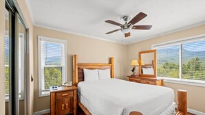 A bedroom with a wooden bed, a nightstand, a lamp, and a ceiling fan. - Sleeps 4 Mountains Views Indoor Pool Sauna (Gatlinburg)